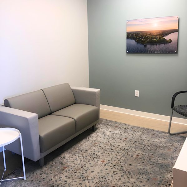 Client room with a gray couch and one white wall, one gray wall with a painting